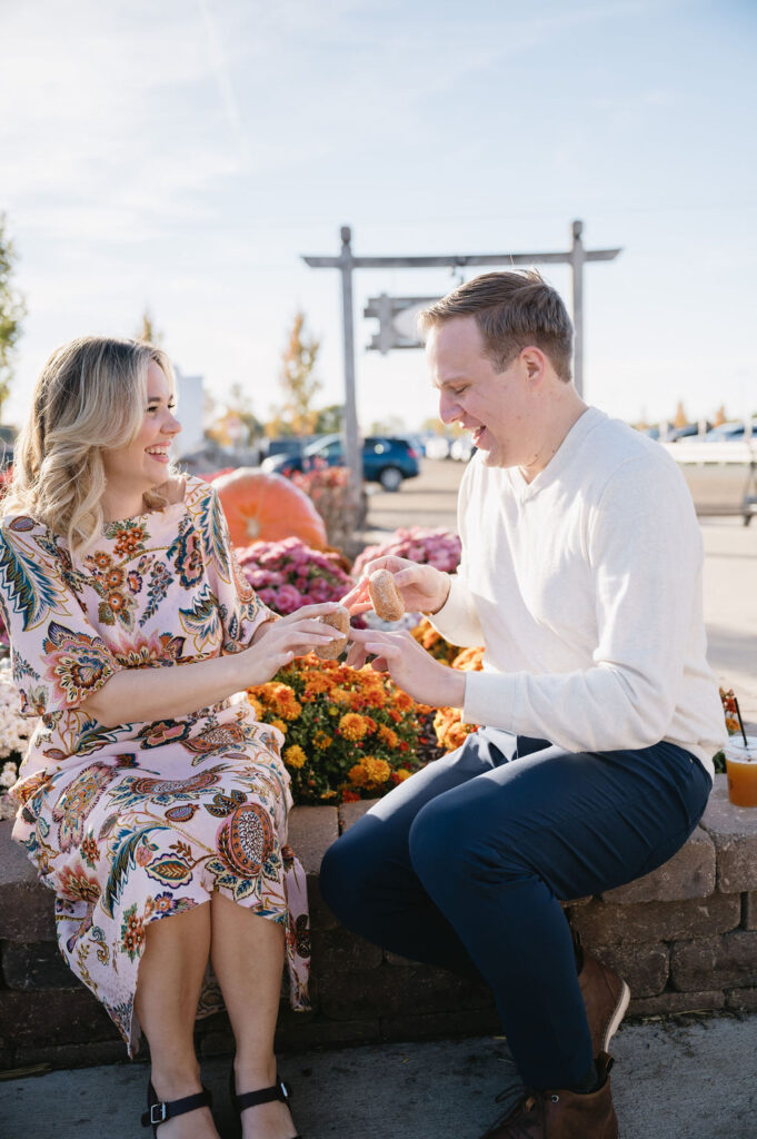 engaged couple holding cider donuts