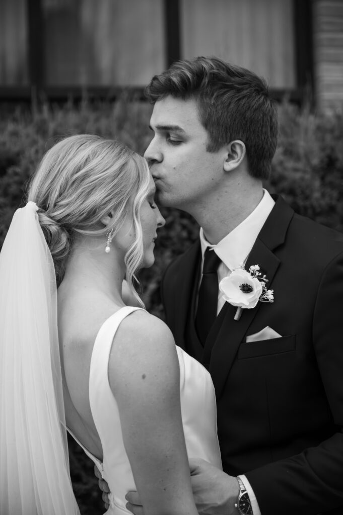 groom kissing bride's forehead in front of The Palazzo Grande, a wedding venue in Sterling Heights Michigan