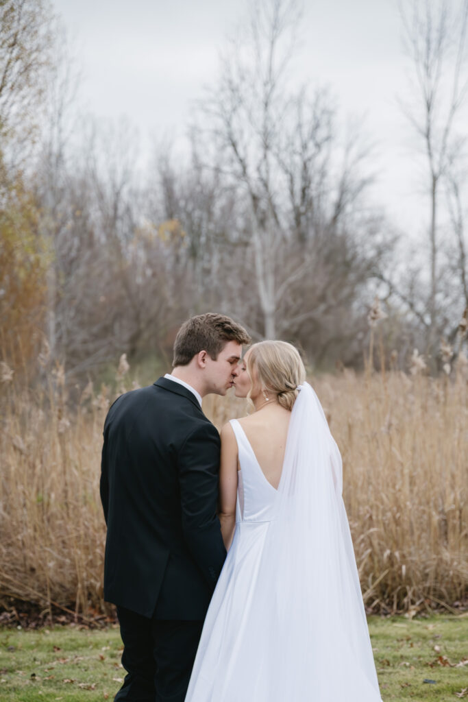 bride and groom kissing in open field by The Palazzo Grande, a wedding venue in Sterling Heights Michigan