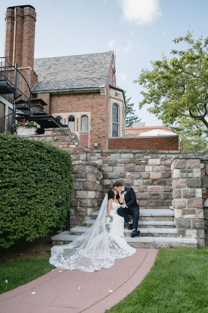 bride and groom sitting on stairs to michigan wedding venue