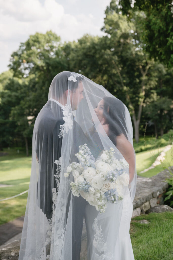 bride and groom under veil on golf course