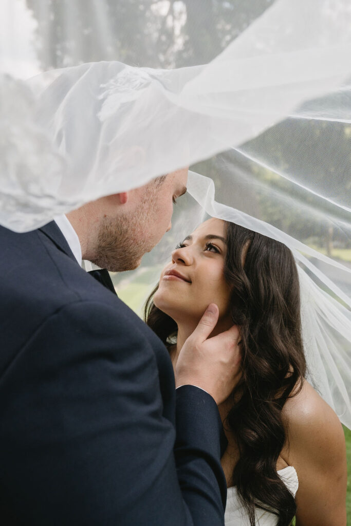 bride and groom under a veil on golf course