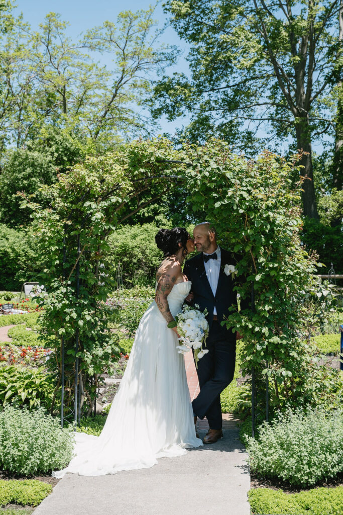 bride and groom standing under arbor in War Memorial gardens