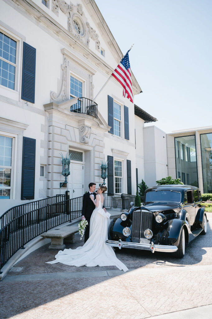 bride and groom standing next to vintage car outside of the War Memorial wedding venue
