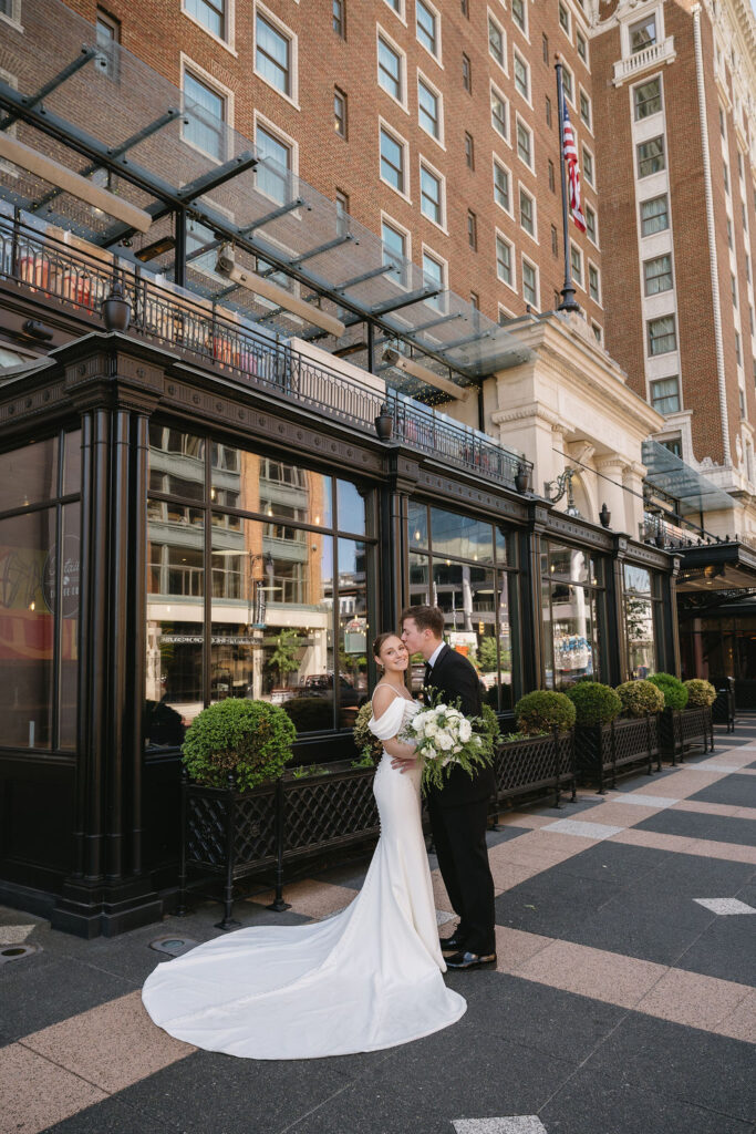 bride and groom kissing outside hotel lobby