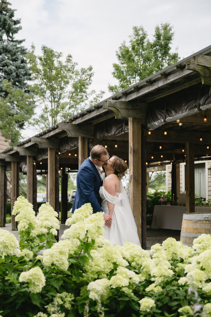 bride and groom kissing behind hydrangeas