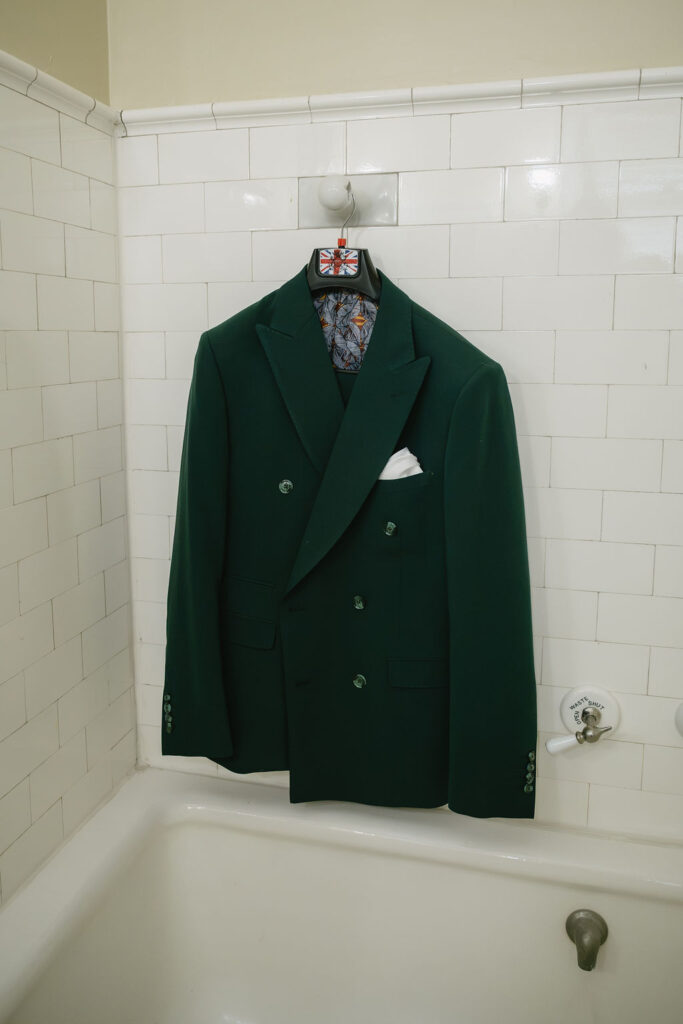 green suit jacket hanging in bathtub