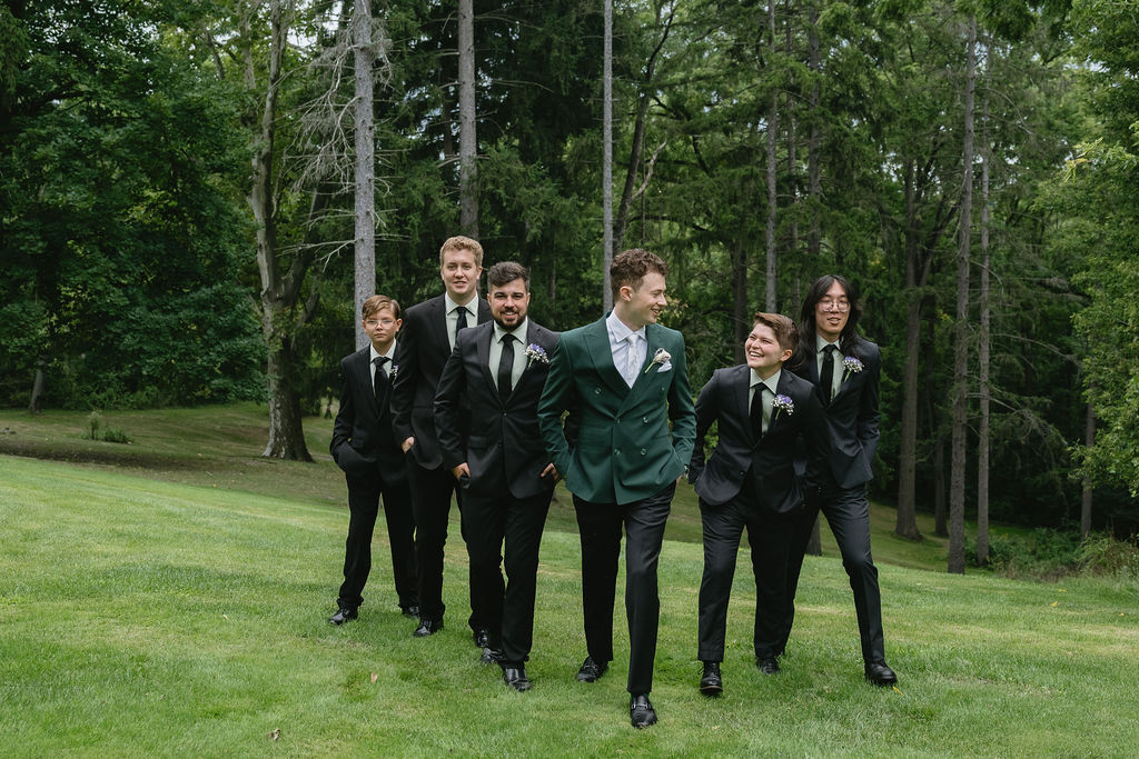 groom and groomsmen walking on grass