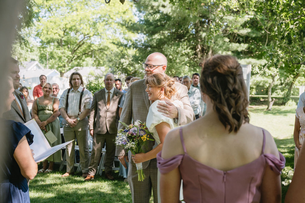 father hugging bride at wedding ceremony