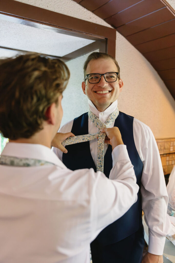 groom tying floral tie