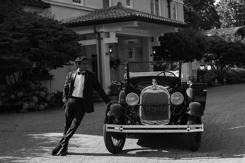 groom leaning on antique car outside belvedere estate