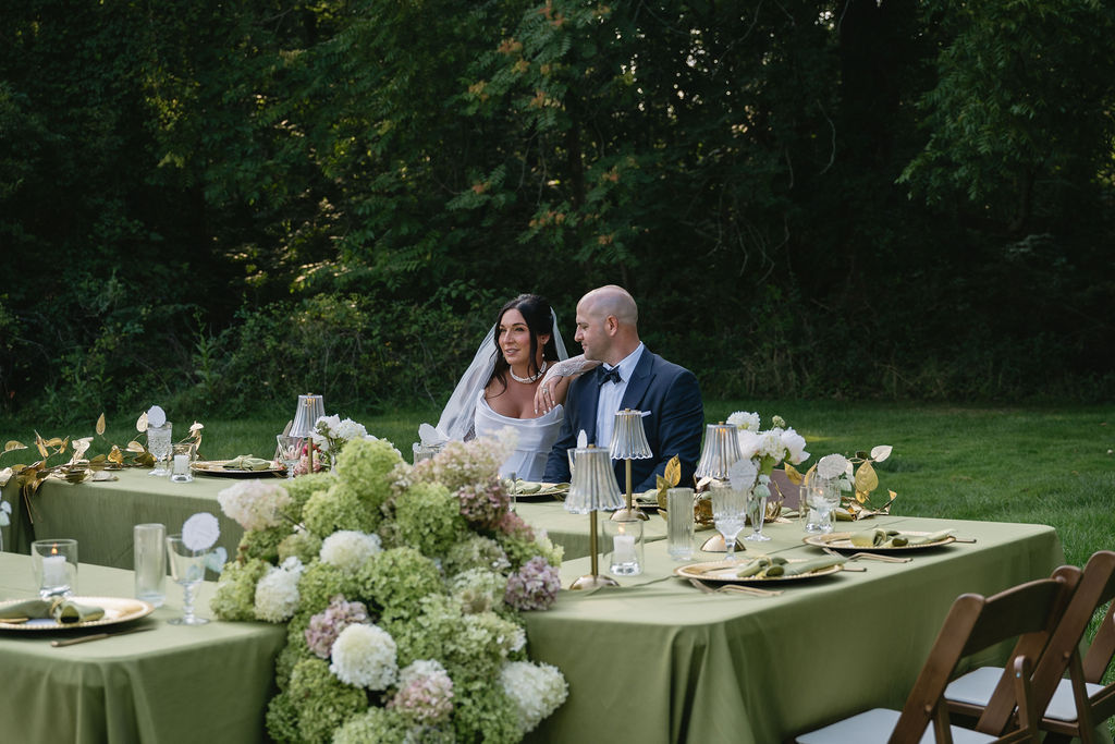bride and groom sitting at outdoor wedding reception table