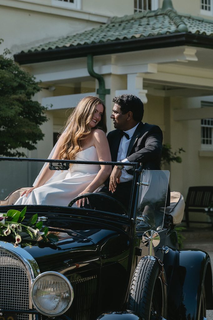 bride and groom sitting in antique car outside belvedere estate