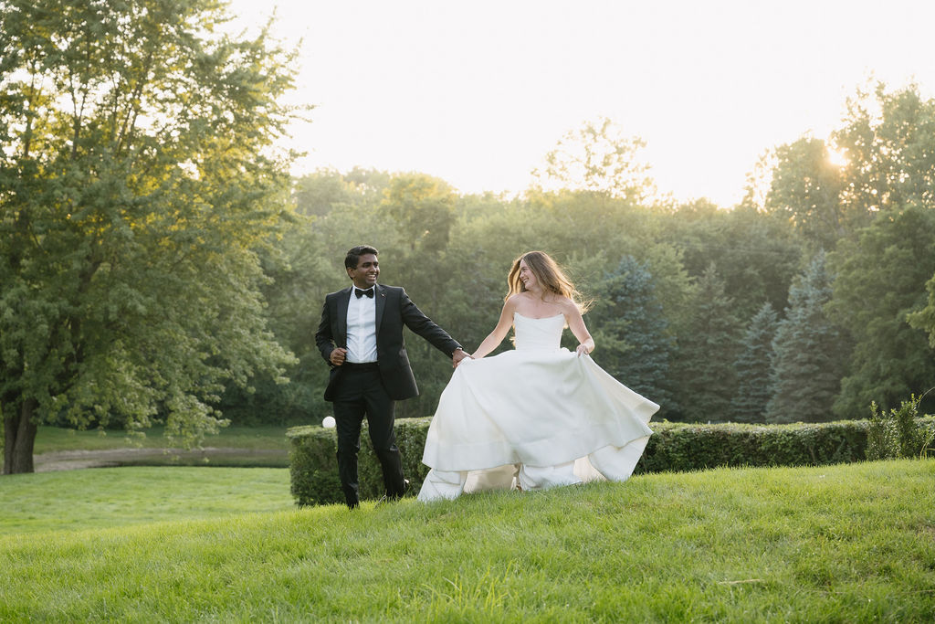 bride and groom running through field at belvedere estate